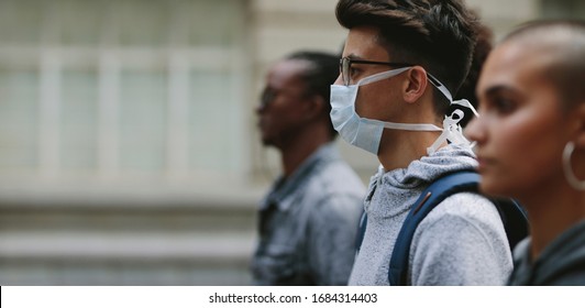Young man wearing a mask participating in a protest with people around. Young people on a silent protest in the city.