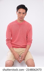 Young Man Wearing Orange Sweater With Khaki Shorts Sitting Wooden Cube In Studio