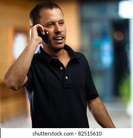 Young Man Wearing Polo Shirt Talking On Mobile Phone