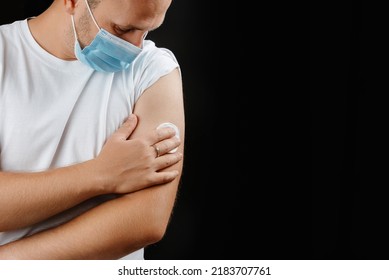 A young man wearing a protective mask holds on to the injection site. A man and a cold and pandemic vaccination. Covid 19. Vaccination for diseases. Copy space - Powered by Shutterstock