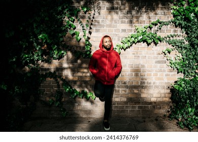 Young man wearing red hoodie leaning against a wall - Powered by Shutterstock