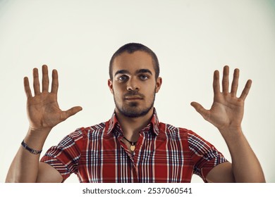 Young man wearing a red plaid shirt is pointing to an invisible screen on a white background, as if he is interacting with data or a presentation - Powered by Shutterstock