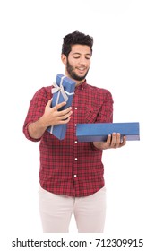 Young Man Wearing Red Shirt And White Pants, Happy Smiling Guy Holding A Gift Box, Isolated On White Background