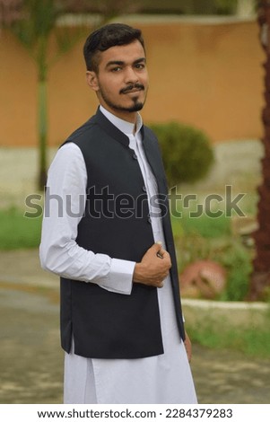 A young man wearing shalwar kameez, the national dress of Pakistan.