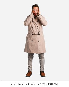 Young Man Wearing Trench Coat Surprised And Shocked