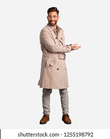 Young Man Wearing Trench Coat Holding Something With Hands