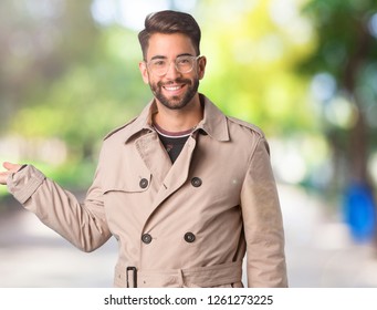 Young Man Wearing Trench Coat Holding Something With Hand