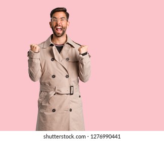 Young Man Wearing Trench Coat Surprised And Shocked