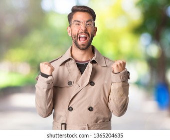 Young Man Wearing Trench Coat Surprised And Shocked