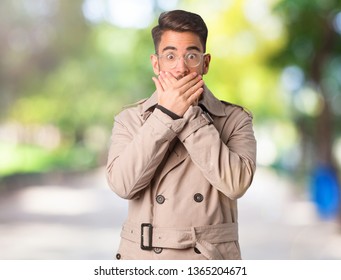 Young Man Wearing Trench Coat Surprised And Shocked