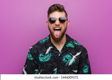 Young man wearing a vacation look funny and friendly sticking out him tongue.