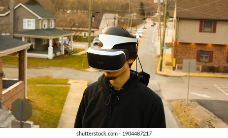 Young Man Wearing A VR Headset With A Suburban Street Behind Him