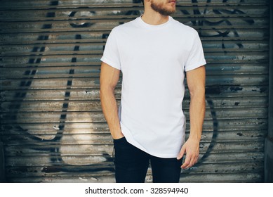 Young man wearing white blank t-shirt and blue jeans, standing on the street