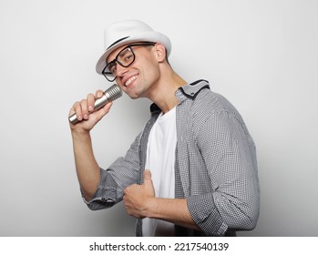 Young Man Wearing White Hat Singing With Microphone Over Grey Background