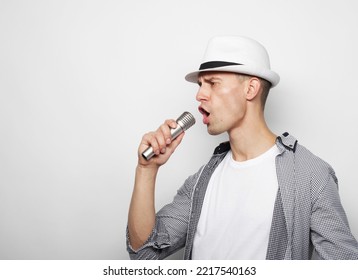 Young Man Wearing White Hat Singing With Microphone Over Grey Background