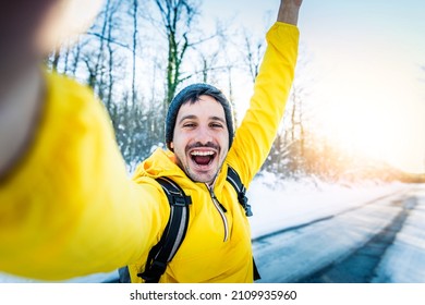 Young Man Wearing Winter Clothes Taking Selfie Picture In Winter Snow Forest - Happy Guy With Backpack Hiking Outside - Recreation, Sport And People Concept