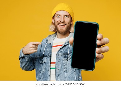 Young man wears denim shirt hoody beanie hat casual clothes hold in hand use point finger on mobile cell phone with blank screen workspace area isolated on plain yellow background. Lifestyle concept - Powered by Shutterstock