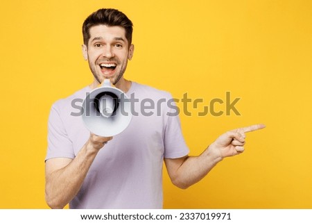 Young man wears light purple t-shirt casual clothes hold in hand megaphone scream announces discounts sale Hurry up point aside isolated on plain yellow background studio portrait. Lifestyle concept