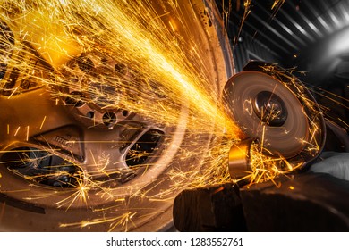 A young man welder in a blue gloves grinder  bearing metal an angle grinder   in the   workshop, sparks fly to the side - Powered by Shutterstock