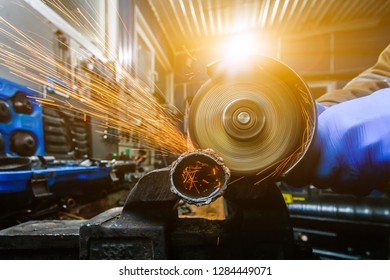 A young man welder in a blue gloves grinder metal an angle grinder   in the   workshop, sparks fly to the side - Powered by Shutterstock