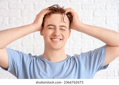 Young man with wet hair on white brick background - Shutterstock ID 2366762673