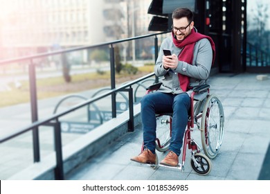 Young Man In The Wheelchair Moving And Using Phone