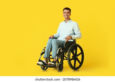 Young man in wheelchair on color background