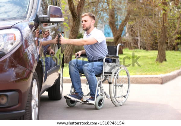 Young\
man in wheelchair opening door of his van\
outdoors