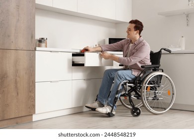 Young man in wheelchair repairing kitchen drawer at home - Powered by Shutterstock