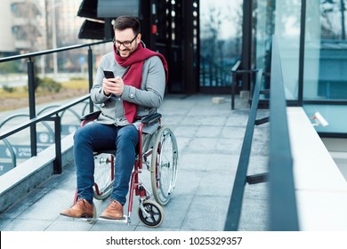 Young Man In The Wheelchair Using His Phone