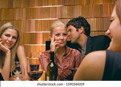 Young Man Whispering In Woman's Ear At Party