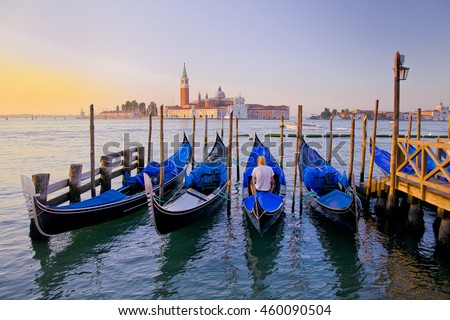 Young man in white clothes sitting in front of Grand Canal in Venice with gondolas against San Giorgio Maggiore church in Italy. Scenery from summer vacation with beautiful colorful morning light. 
