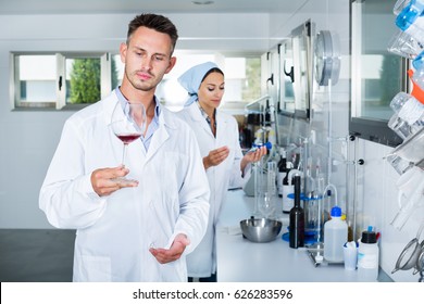 Young man in white coat checking wine acidity and sugar saturation in chemical laboratory on the winery  - Shutterstock ID 626283596