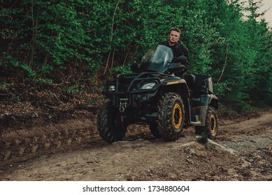 A Young Man In A White Helmet Rides Through The Woods On A Quad Bike. Extreme Hobby. A Trip To ATV On The Road From Logs. Quad Biking Through The Forest.