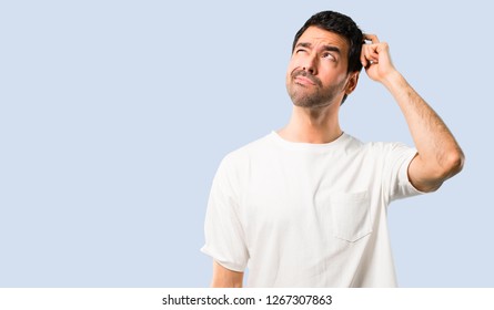 Молодой человек с белой рубашкой, имеющий сомнения и с запутанным выражением лица, царапая голову на изолированном синем фоне