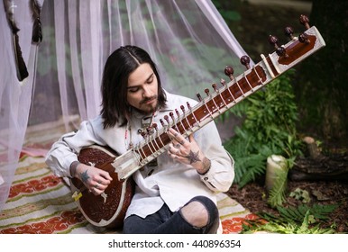 Young man in a white tent, playing guitar, musician, inspiration