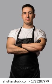 A young man in a white T-shirt with a black apron. crossed arms in black latex gloves on the chest