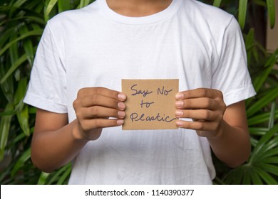 Young man in white t-shirt holding cardboard paper written with word "Say No to Plastic" in a bid to fight plastic pollution.