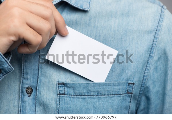 Young man who takes out blank business card from the pocket of his shirt