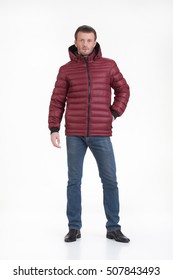 Young Man In A Winter Down Jacket On An Isolated Studio Background