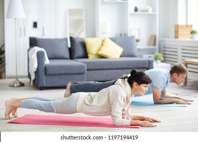 Young Man And Woman In Activewear Doing Plank During Workout At Home