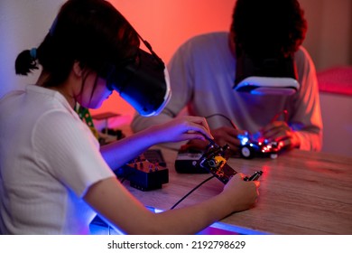 Young Man And Young Woman Amateur Inventor Testing Electronic Device Model Inventions All Wear Vr Glasses To Show High Technology In Black Light Mood.