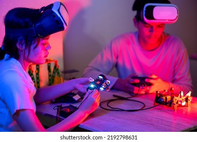 Young Man And Young Woman Amateur Inventor Testing Electronic Device Model Inventions All Wear Vr Glasses To Show High Technology In Black Light Mood.