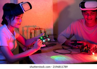 Young Man And Young Woman Amateur Inventor Testing Electronic Device Model Inventions All Wear Vr Glasses To Show High Technology In Black Light Mood.