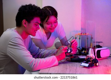 Young Man And Young Woman Amateur Inventor Testing Electronic Device Model Inventions With In Black Light Mood.