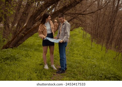 A young man and woman arguing in the forest. The young couple got lost in the woods, holding a paper map. Searching for their location in the forest, orienteering.