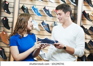 Young Man And Woman Assistant Choosing Footwear During Shopping At Shoe Shop