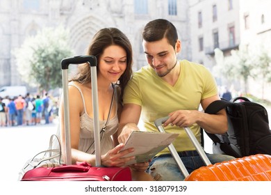 Young man and woman with a backpack and suitcases studying a city map - Powered by Shutterstock