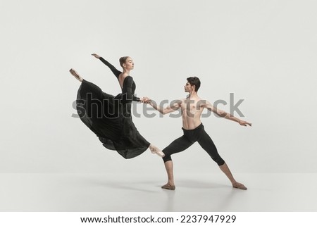 Young man and woman, ballet dancers performing isolated over grey studio background. Flying high. Concept of classical dance aesthetics, choreography, art, beauty. Copy space for ad