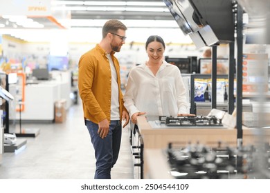 Young man and woman buying new gas stove in appliances shop.